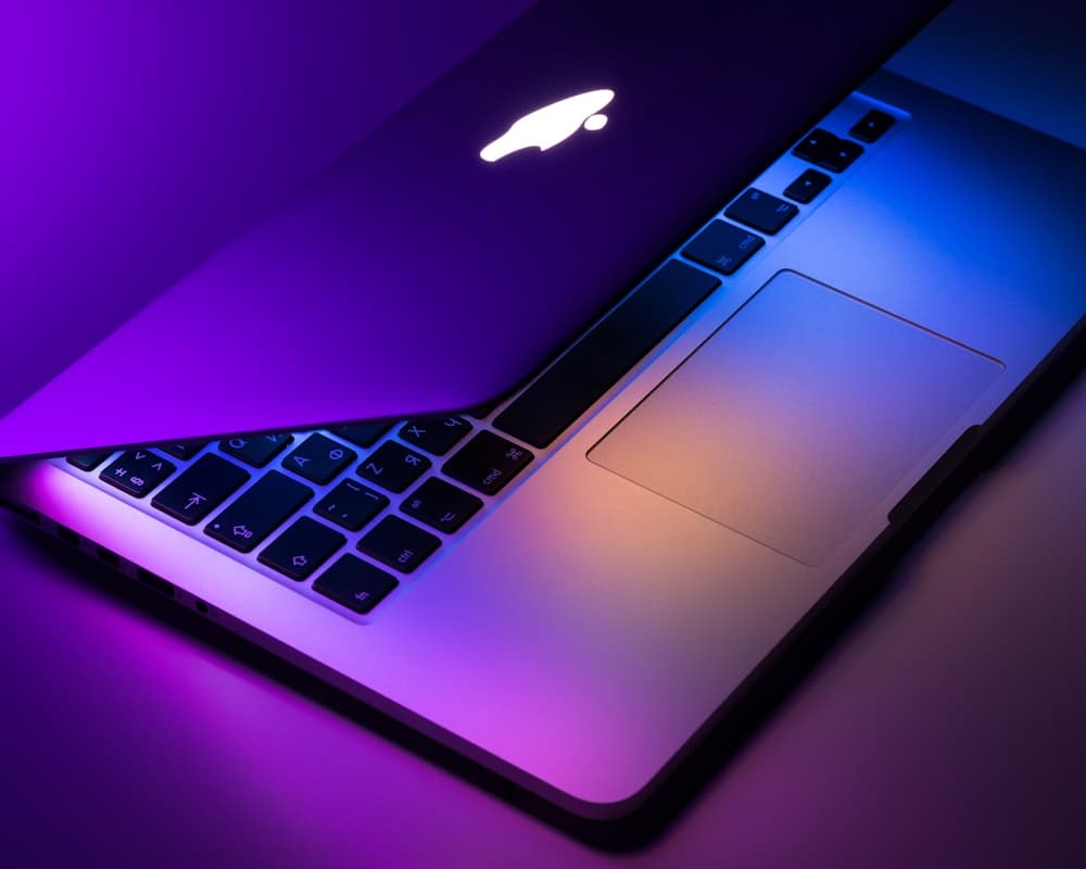 MacBook Pro entrouvert sous une lumière colorée (photo d'illustration)