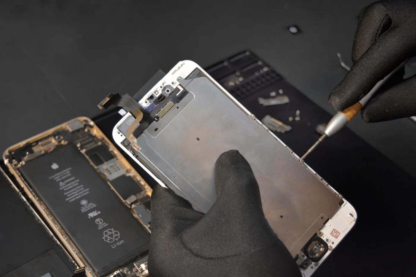 Technicien remplaçant l'écran d'un smartphone avec des gants et un tournevis de précision